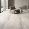 Sala luminosa con ventanas grandes, sofá color gris oscuro y un piso de cerámica mármol Vittoria